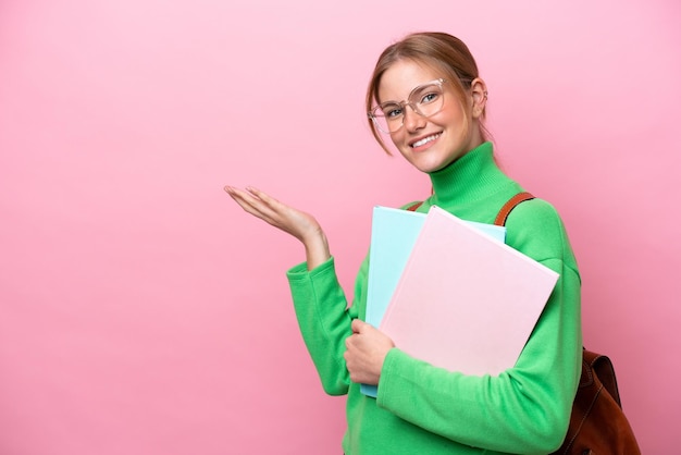 Young caucasian student woman isolated on pink background extending hands to the side for inviting to come