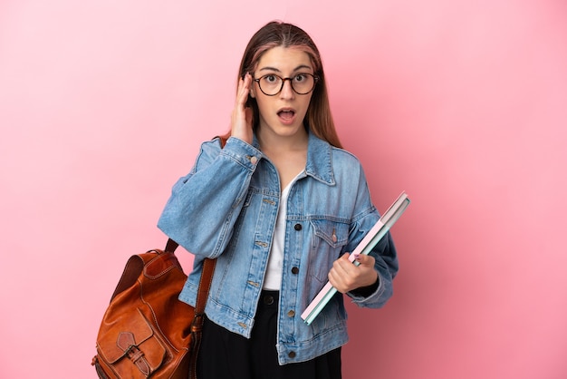 Young caucasian student woman isolated on pink wall with surprise and shocked facial expression