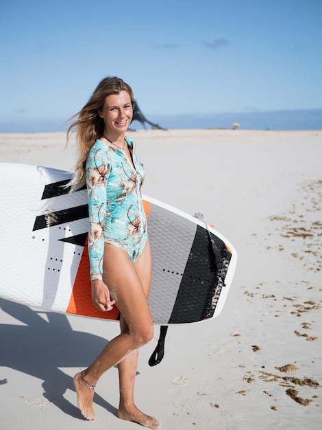 ビーチで水中翼サーフボードを保持している若い白人サーファー女性