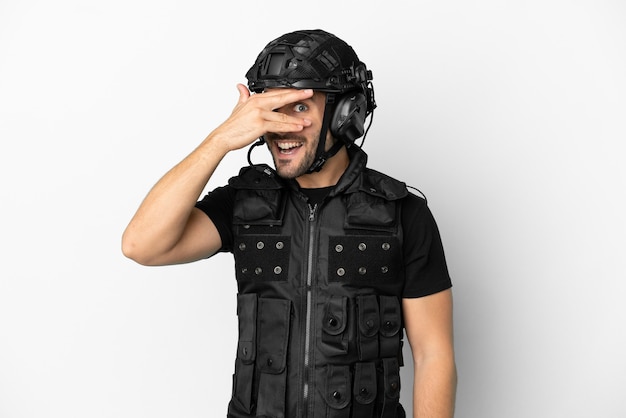 Young caucasian swat isolated on white background covering eyes by hands and smiling