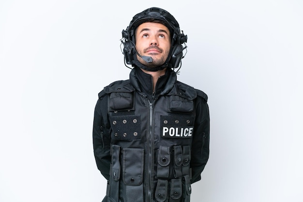Young caucasian SWAT man isolated on white background and looking up