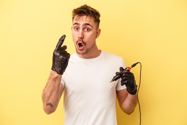 Young caucasian tattoo maker man isolated on yellow background having an idea, inspiration concept.