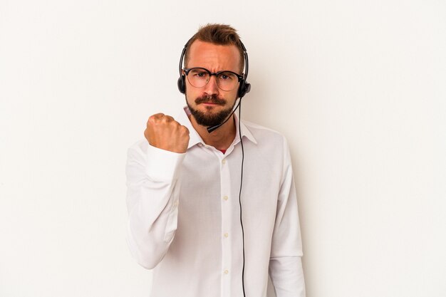 Foto giovane uomo caucasico telemarketer con tatuaggi isolati su sfondo bianco che mostra pugno alla telecamera, espressione facciale aggressiva.