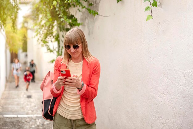 Young caucasian tourist woman smiling happy using smartphone at street of city