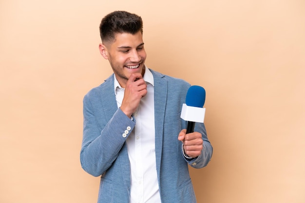 Foto giovane presentatore televisivo caucasico isolato su sfondo bianco che guarda al lato e sorridente