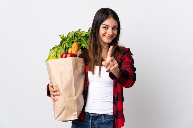 Young caucasian with vegetables isolated on white showing and lifting a finger