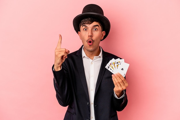 Young caucasian wizard man holding a magic cards isolated on\
white background having some great idea, concept of\
creativity.