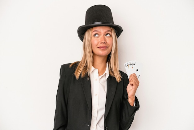 Young caucasian wizard woman holding magic card isolated on white background dreaming of achieving goals and purposes