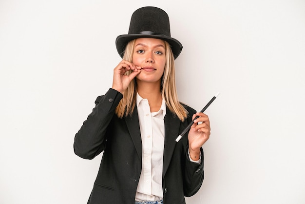 Young caucasian wizard woman holding wand isolated on white background with fingers on lips keeping a secret.