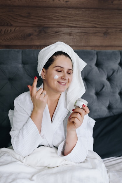 Young caucasian woman applying face cream on her face