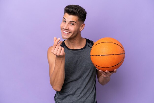 Young caucasian woman basketball player man isolated on purple\
background making money gesture