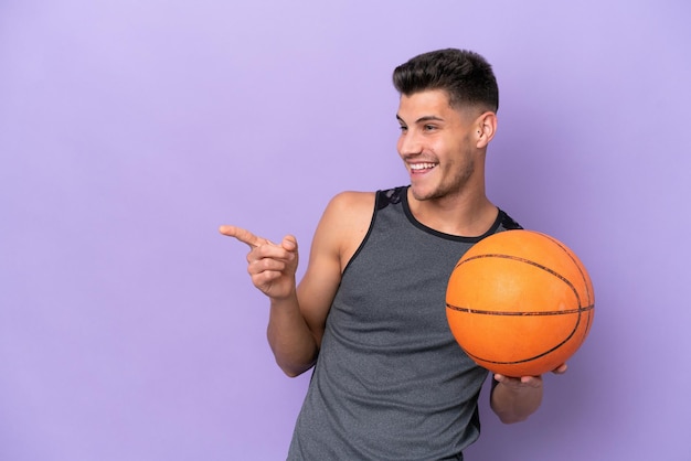 Young caucasian woman basketball player man isolated on purple background pointing finger to the side and presenting a product