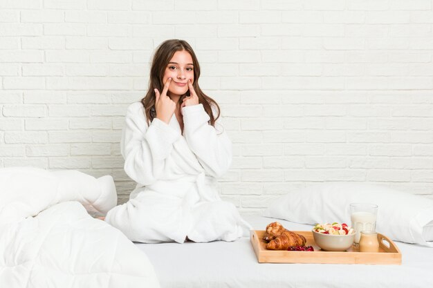 Young caucasian woman on the bed doubting between two options.