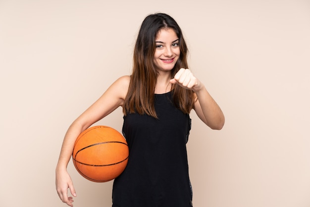 Young caucasian woman on beige wall playing basketball and proud of himself