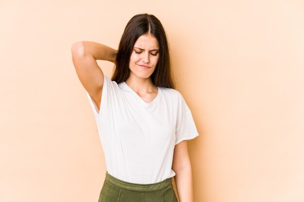 Young caucasian woman on beige wall suffering neck pain