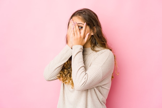 Young caucasian woman blink through fingers frightened and nervous.