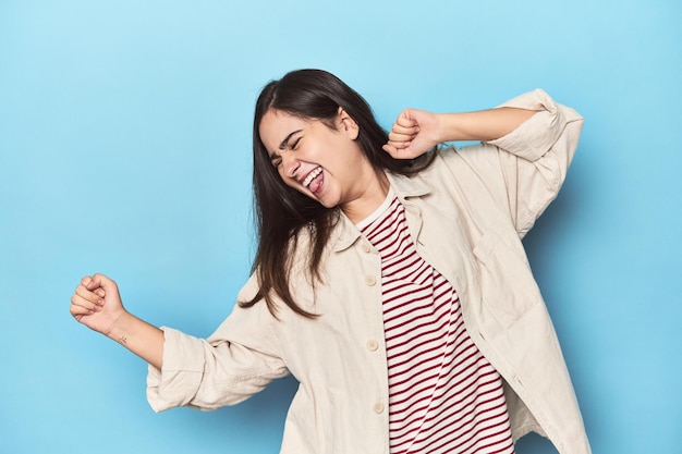 Young Caucasian woman on blue backdrop dancing and having fun