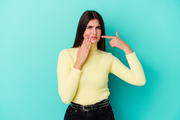 Young caucasian woman on blue having a strong teeth pain, molar ache.