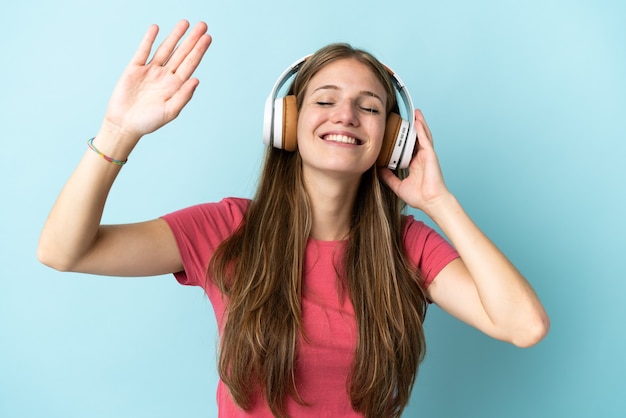 Young caucasian woman on blue listening music and dancing