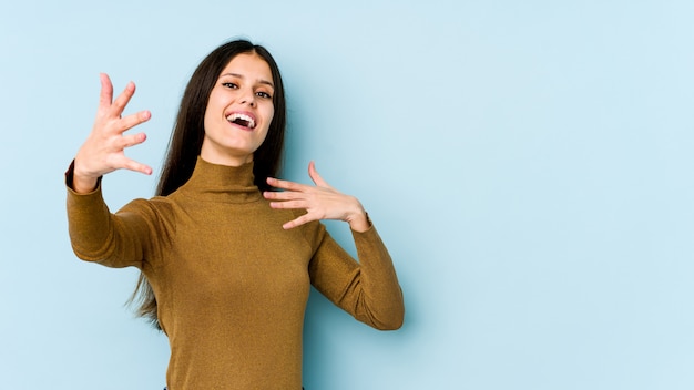 Young caucasian woman on blue wall feels confident giving a hug