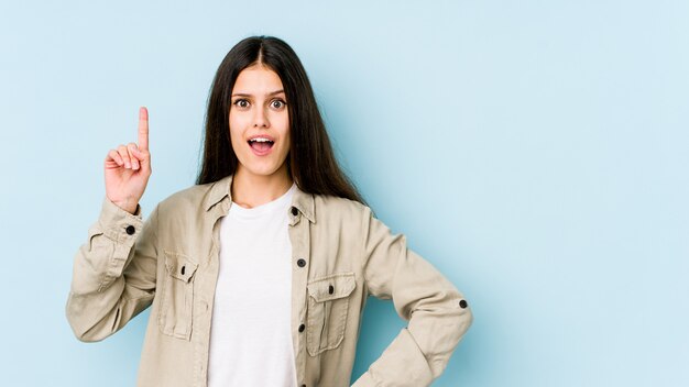 Giovane donna caucasica sulla parete blu che ha un'idea