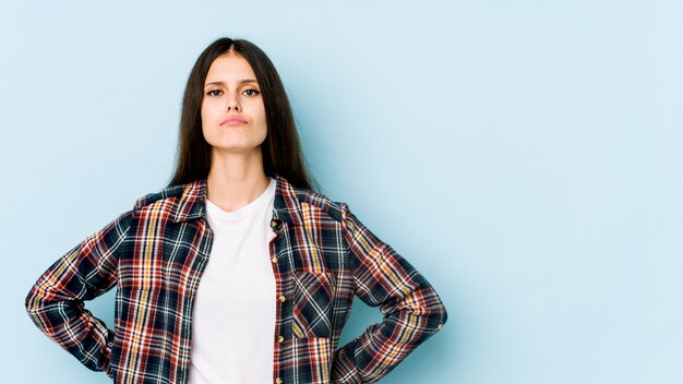 Young caucasian woman on blue wall sad, serious face, feeling miserable and displeased.