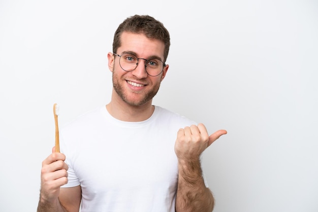 Young caucasian woman brushing teeth isolated on white background pointing to the side to present a product