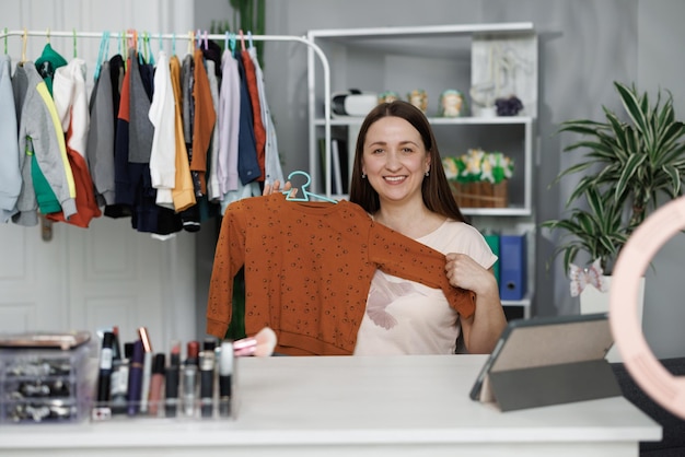 Photo young caucasian woman business owner at fashion store holding smartphone live streaming for sale