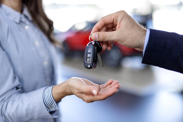 young caucasian woman buys a car at a dealership man seller gives the car keys smiling salesman or manager giving car keys to modern happy woman new car owner