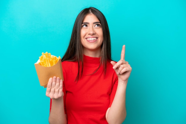 Foto giovane donna caucasica che cattura patatine fritte isolate su sfondo blu che indica una grande idea