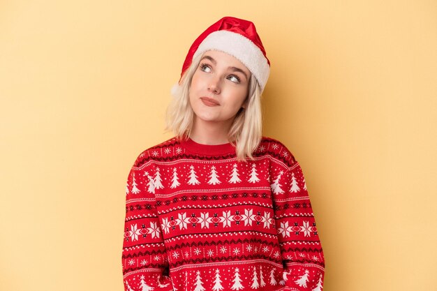 Young caucasian woman celebrating Christmas isolated on yellow background dreaming of achieving goals and purposes