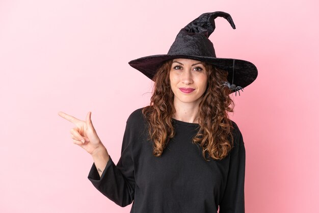 Young caucasian woman celebrating halloween isolated on pink background pointing finger to the side