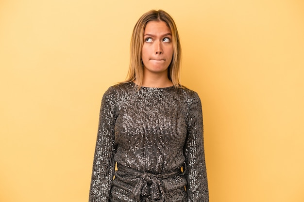 Foto la giovane donna caucasica che celebra il nuovo anno isolata su sfondo giallo confusa, si sente dubbiosa e insicura.