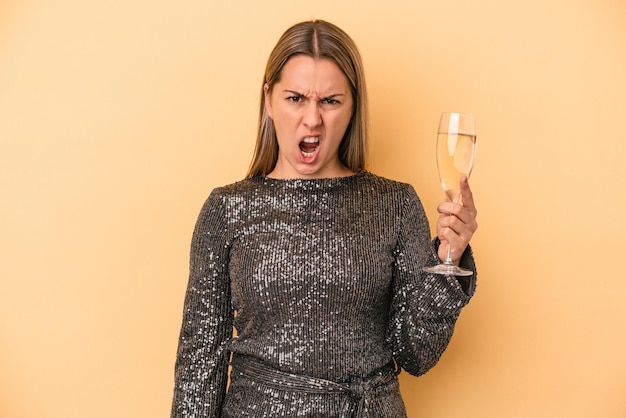 Young caucasian woman celebrating new year isolated on yellow background screaming very angry and aggressive.