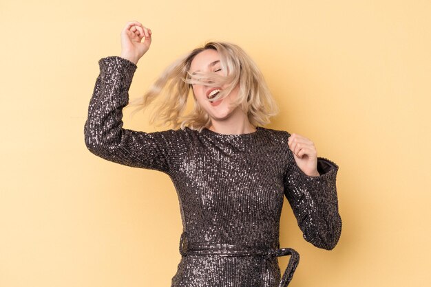 Young caucasian woman celebrating new year isolated on yellow background