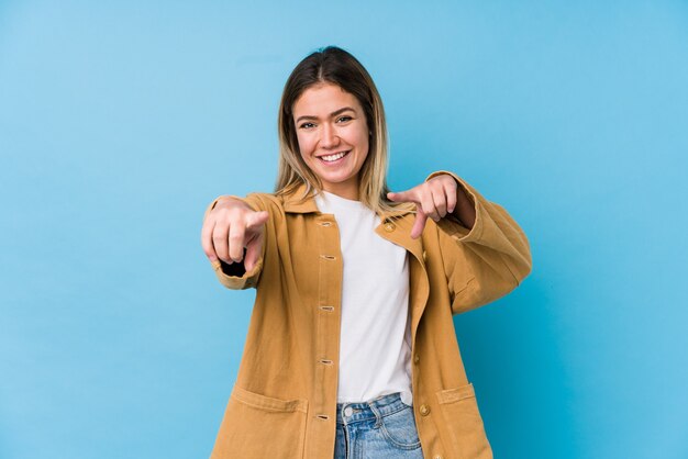 Young caucasian woman cheerful smiles pointing to front.