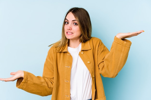 Young caucasian woman confused and doubtful shrugging shoulders to hold a copy space.