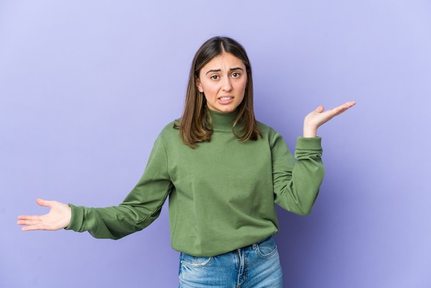 Young caucasian woman confused and doubtful shrugging shoulders to hold a copy space.