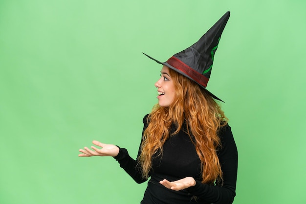 Young caucasian woman costume as witch isolated on green screen chroma key background with surprise facial expression