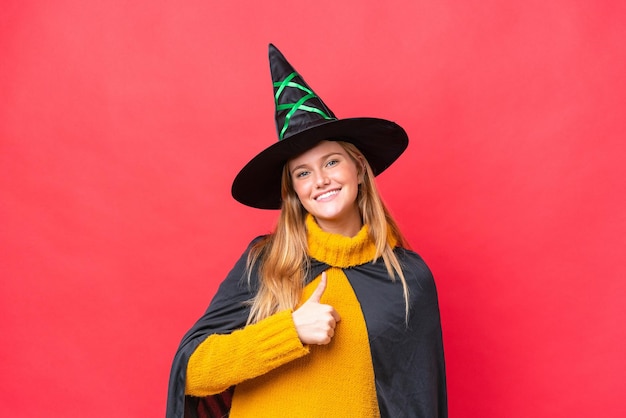 Young caucasian woman costume as witch isolated on red background giving a thumbs up gesture