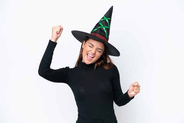 Young caucasian woman costume as witch isolated on white background celebrating a victory