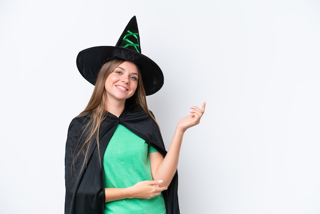 Young caucasian woman costume as witch isolated on white\
background extending hands to the side for inviting to come