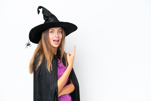 Young caucasian woman costume as witch isolated on white background surprised and pointing side