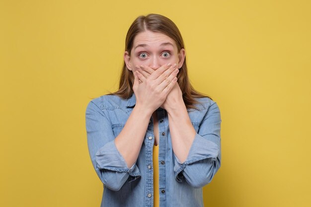 Photo young caucasian woman covering her mouth with hand trying not to tell a secret