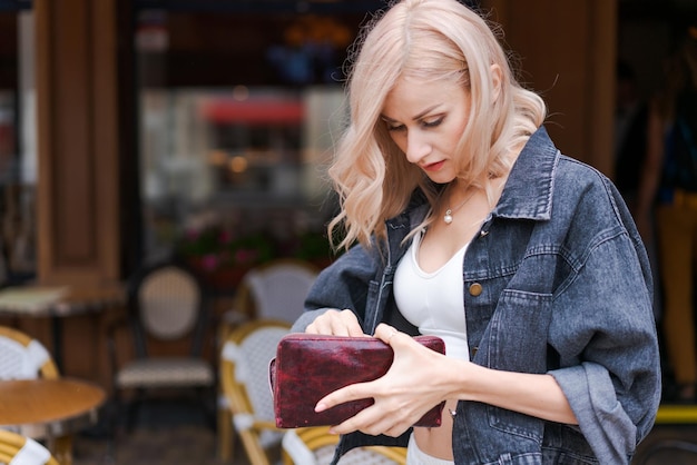 Young caucasian woman decides between paying by credit card or cash while