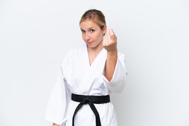 Young caucasian woman doing karate isolated on white background making money gesture