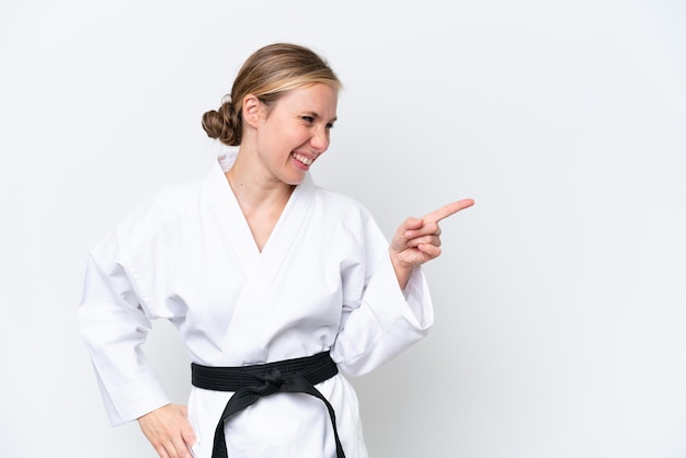 Young caucasian woman doing karate isolated on white background pointing finger to the side and presenting a product