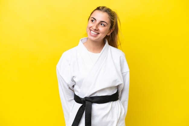 Photo young caucasian woman doing karate isolated on yellow background thinking an idea while looking up