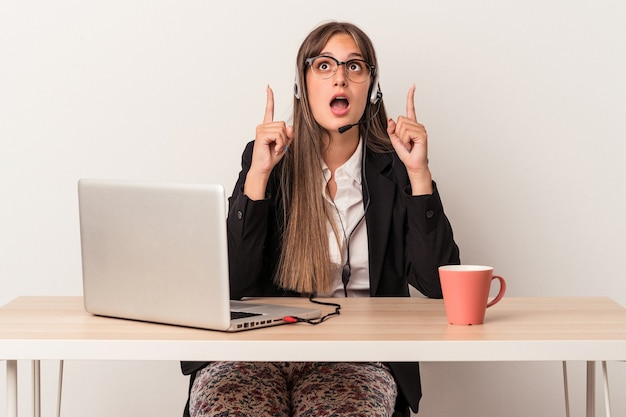 Young caucasian woman doing telecommuting isolated on white background pointing upside with opened mouth.