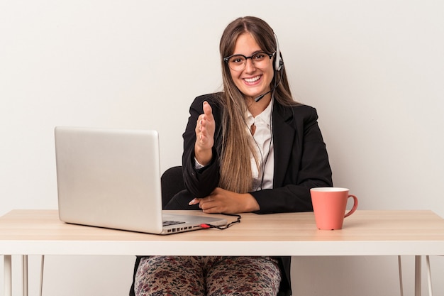 Young caucasian woman doing telecommuting isolated on white background stretching hand at camera in greeting gesture.